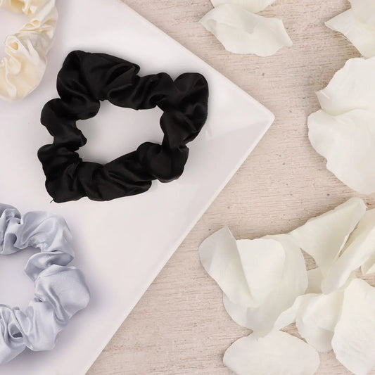 Soft Hair Scrunchies in silver, white, and black on a tray with petals.