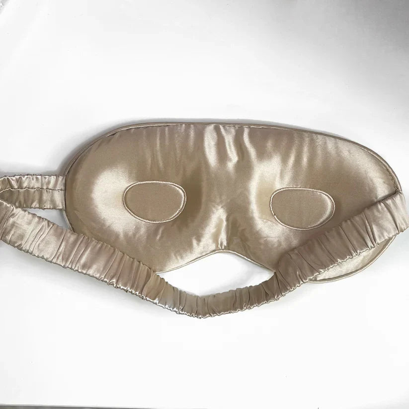 Contoured silk sleep mask in champagne with elasticated strap for comfort.