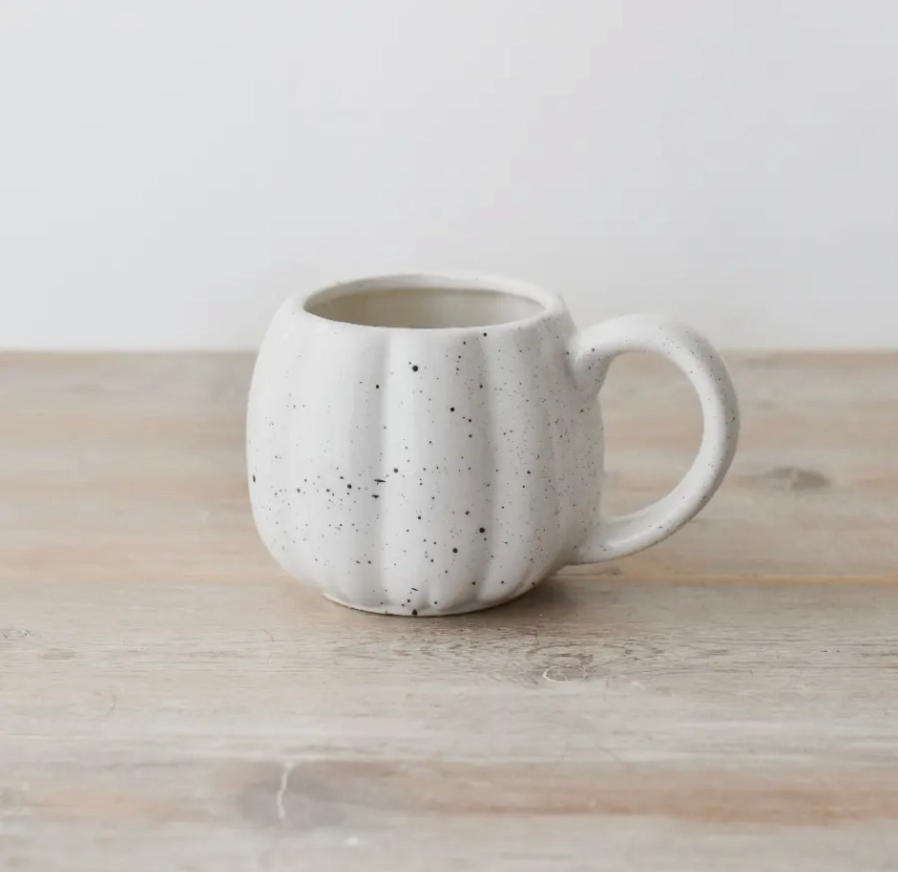 Speckled ceramic pumpkin mug on a wooden surface. autumn Halloween gift mug