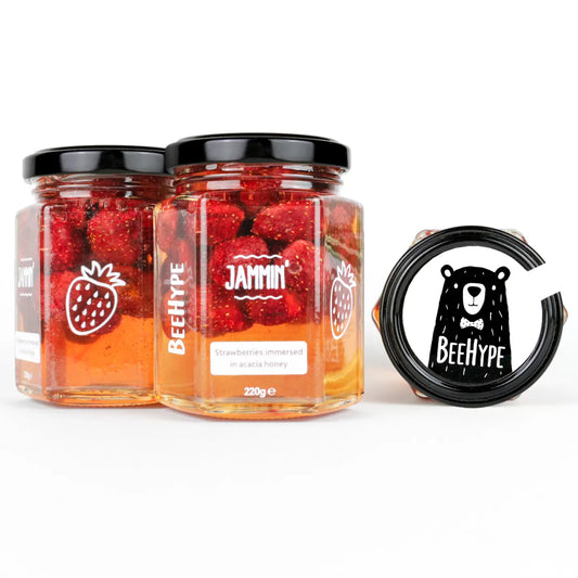 Strawberries preserved in raw acacia honey jars.