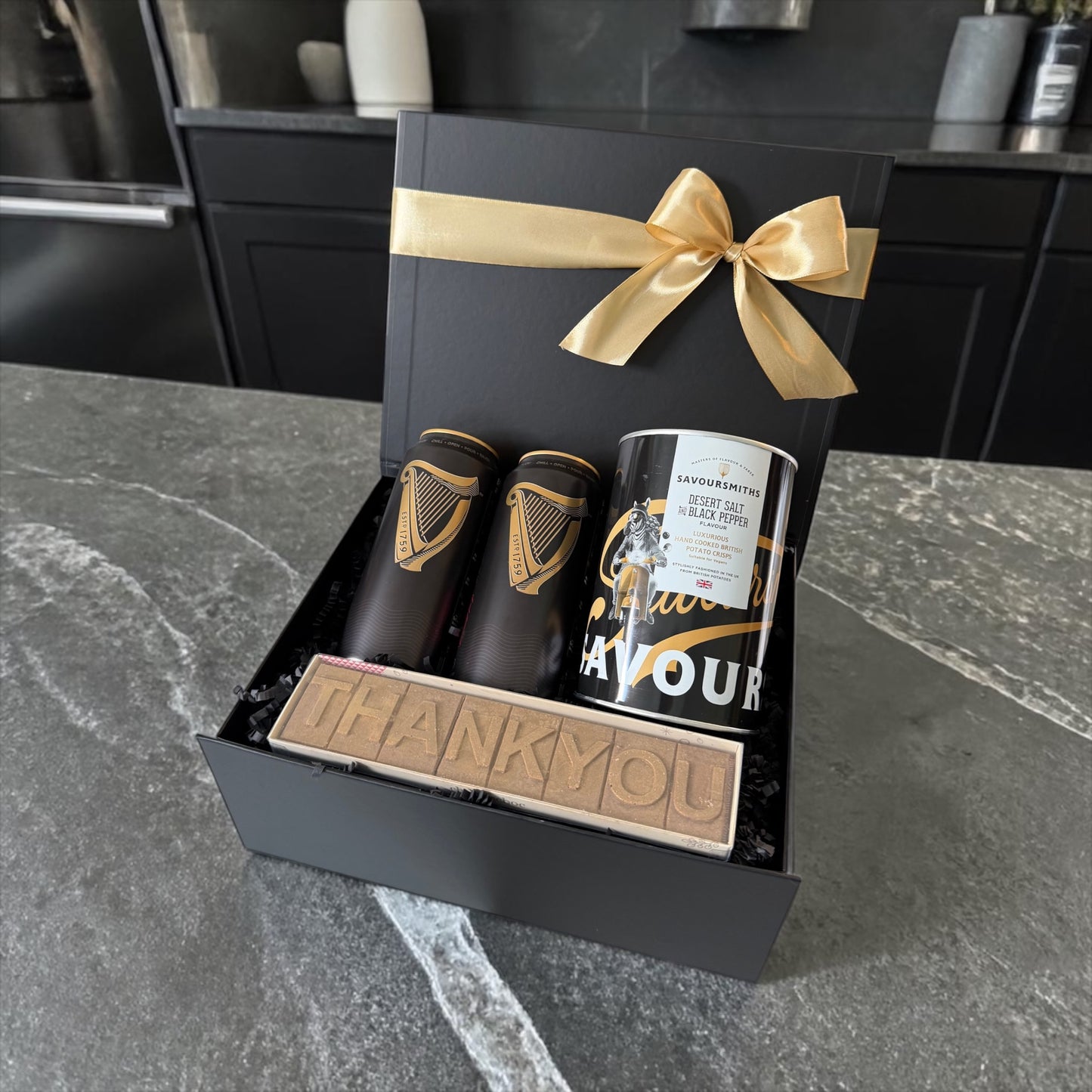 Black gift box with beer, gourmet crisps and thank you chocolate bar tied with gold ribbon