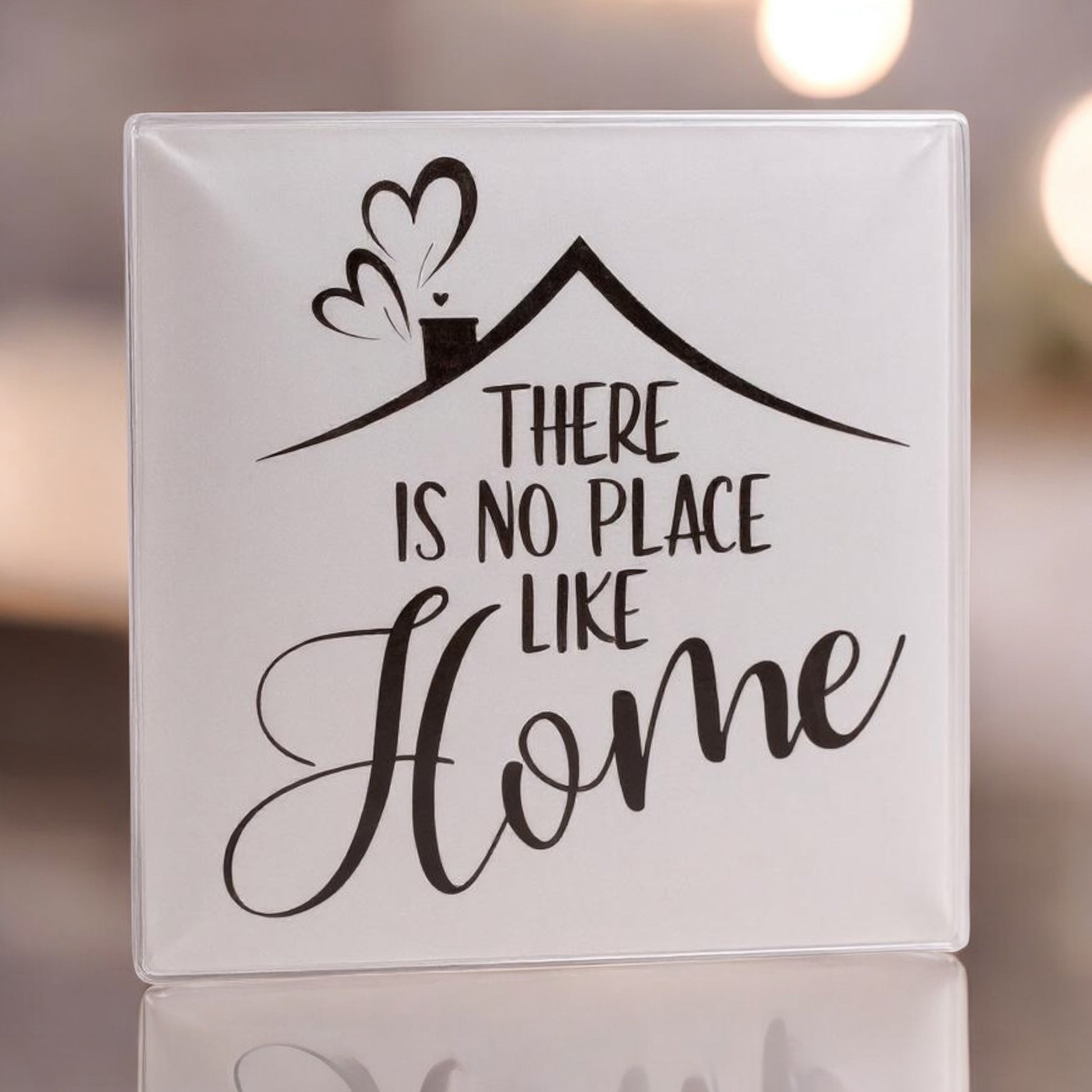 Decorative glass tile with 'There is no place like home' text and house illustration.