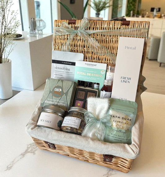 Pampering mum gift hamper with bath salts, truffles, facial steam, socks & relaxation treats in a wicker basket.