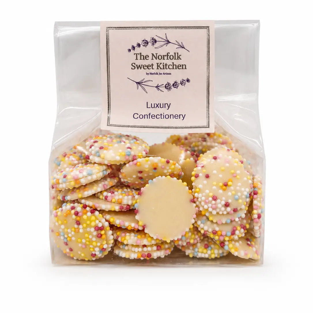 White chocolate discs topped with colourful rainbow sprinkles, creating a fun and crunchy sweet treat.