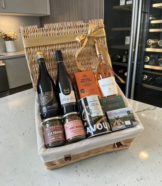 Wine and food gift hamper basket on a kitchen counter with rose, red amarone wine and white pouilly fume wine