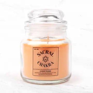Seven Chakra Candle with ylang ylang scent in glass jar for sacral chakra balance and meditation.